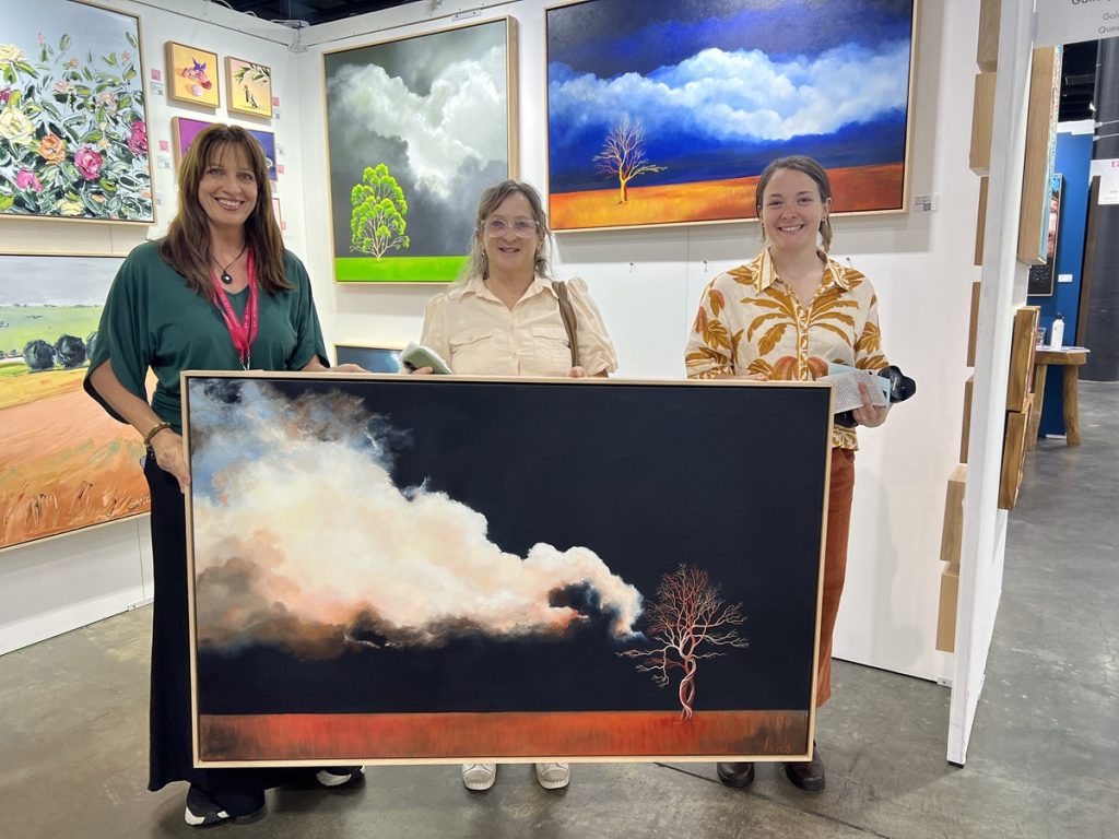 Collectors with a large original atmospheric landscape painting by Lucinda Leveille sold during Affordable Art Fair Brisbane 2026.