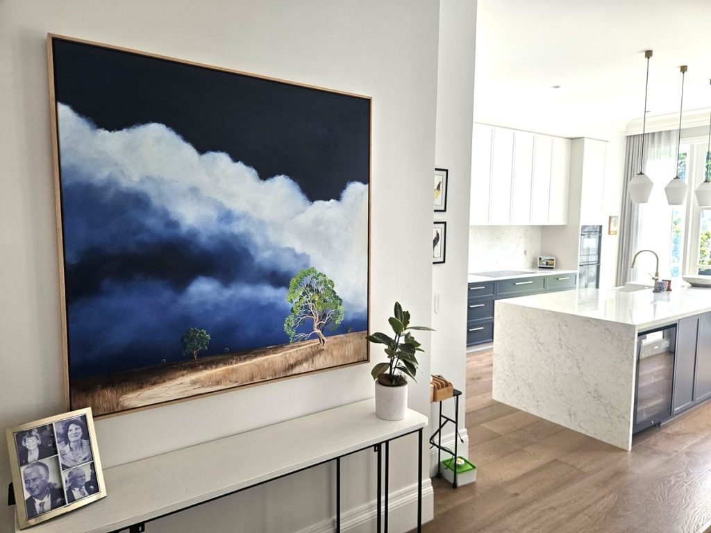 Original atmospheric landscape painting by Lucinda Leveille installed in a contemporary Randwick Sydney interior featuring dramatic storm clouds, open land and a solitary gum tree as a commission piece