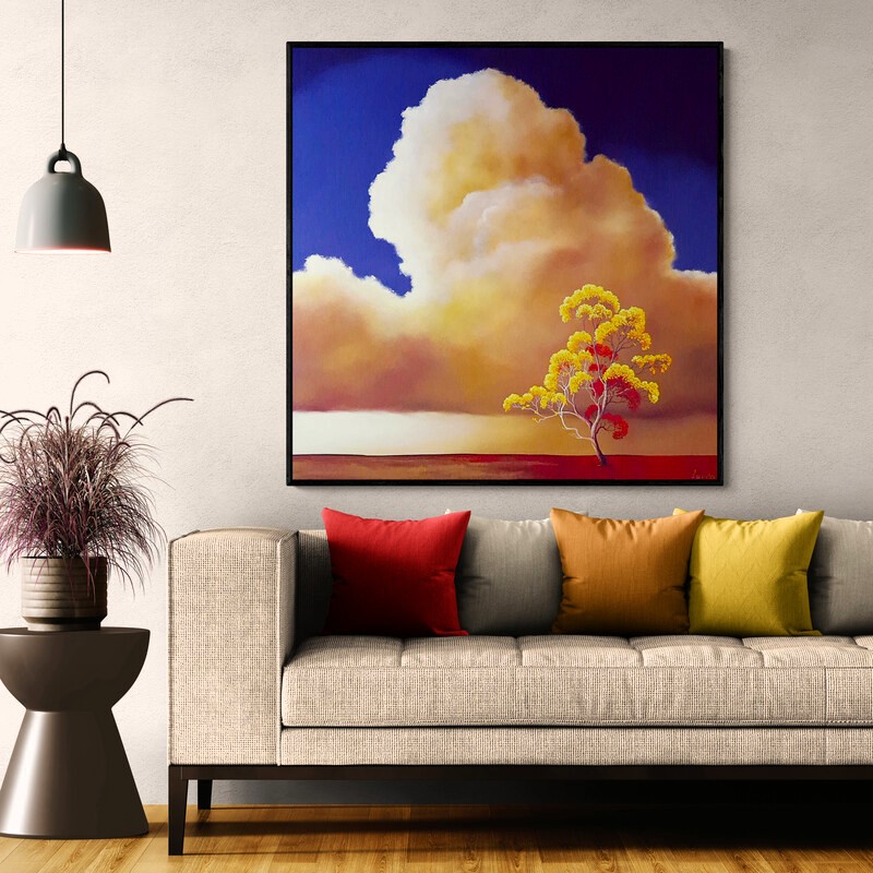 Golden Drift by Lucinda Leveille displayed in a contemporary interior, original Australian landscape painting featuring a towering golden cloud, deep blue sky and flowering yellow tree.