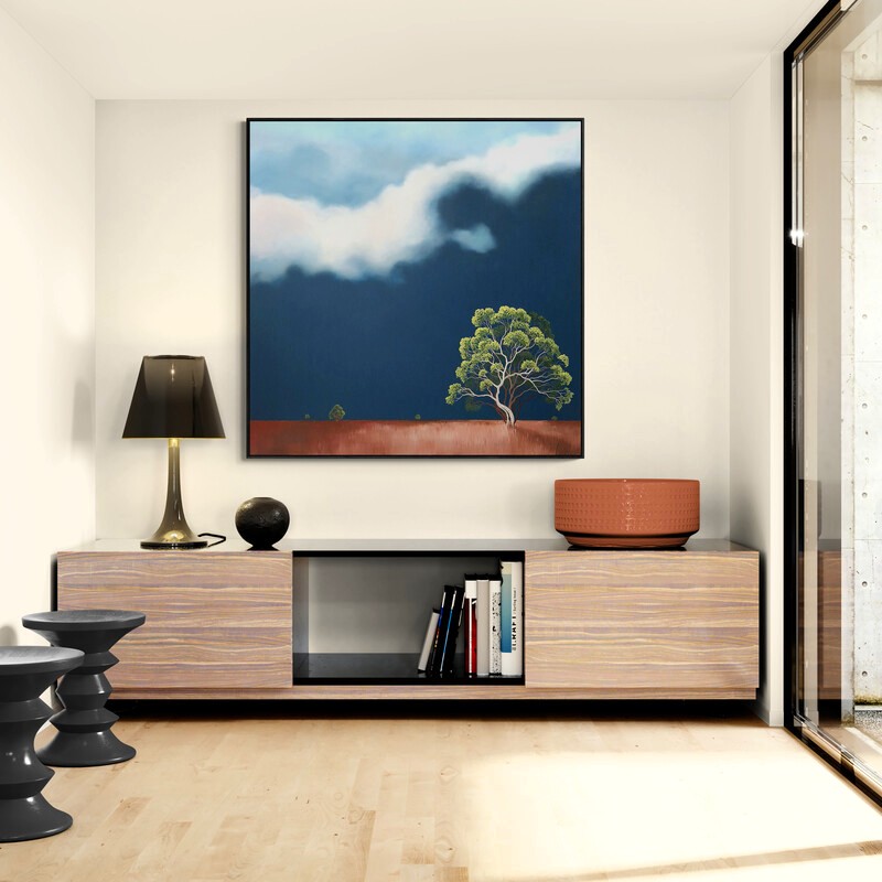 Lonely Sentinel by Lucinda Leveille displayed in a contemporary interior, original Australian landscape painting featuring a solitary tree beneath a dramatic cloud bank and expansive blue sky.