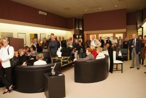 Collectors and art enthusiasts attending a gallery opening, viewing contemporary artworks in a busy exhibition space.